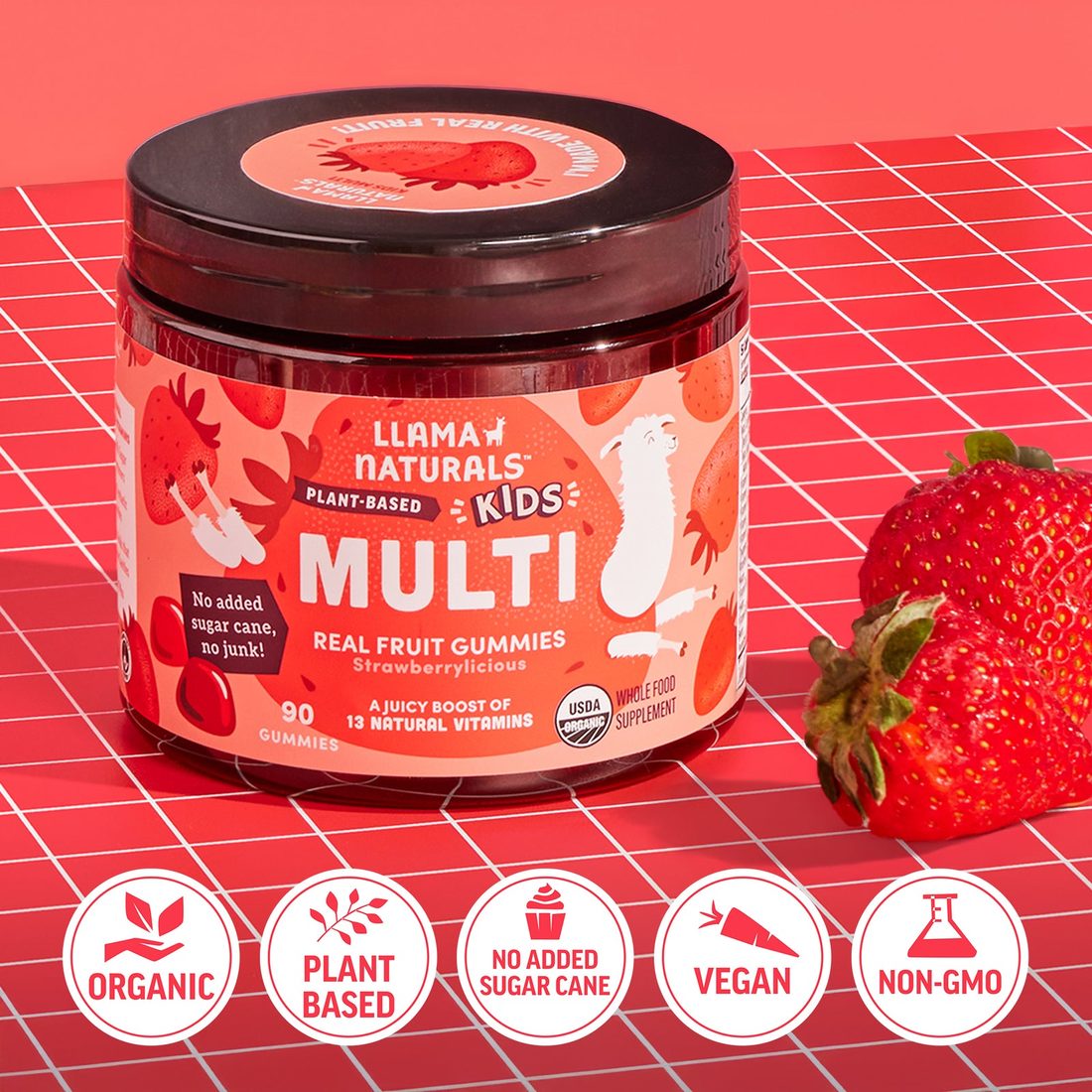 Llama Naturals Kids Multi jar labeled "No added sugar cane, no junk!" next to fresh strawberries